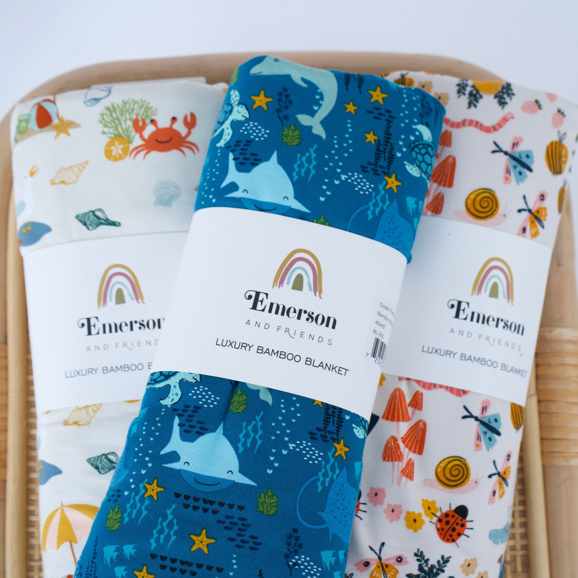 Three Emerson baby blankets with different patterns on a wooden chair.