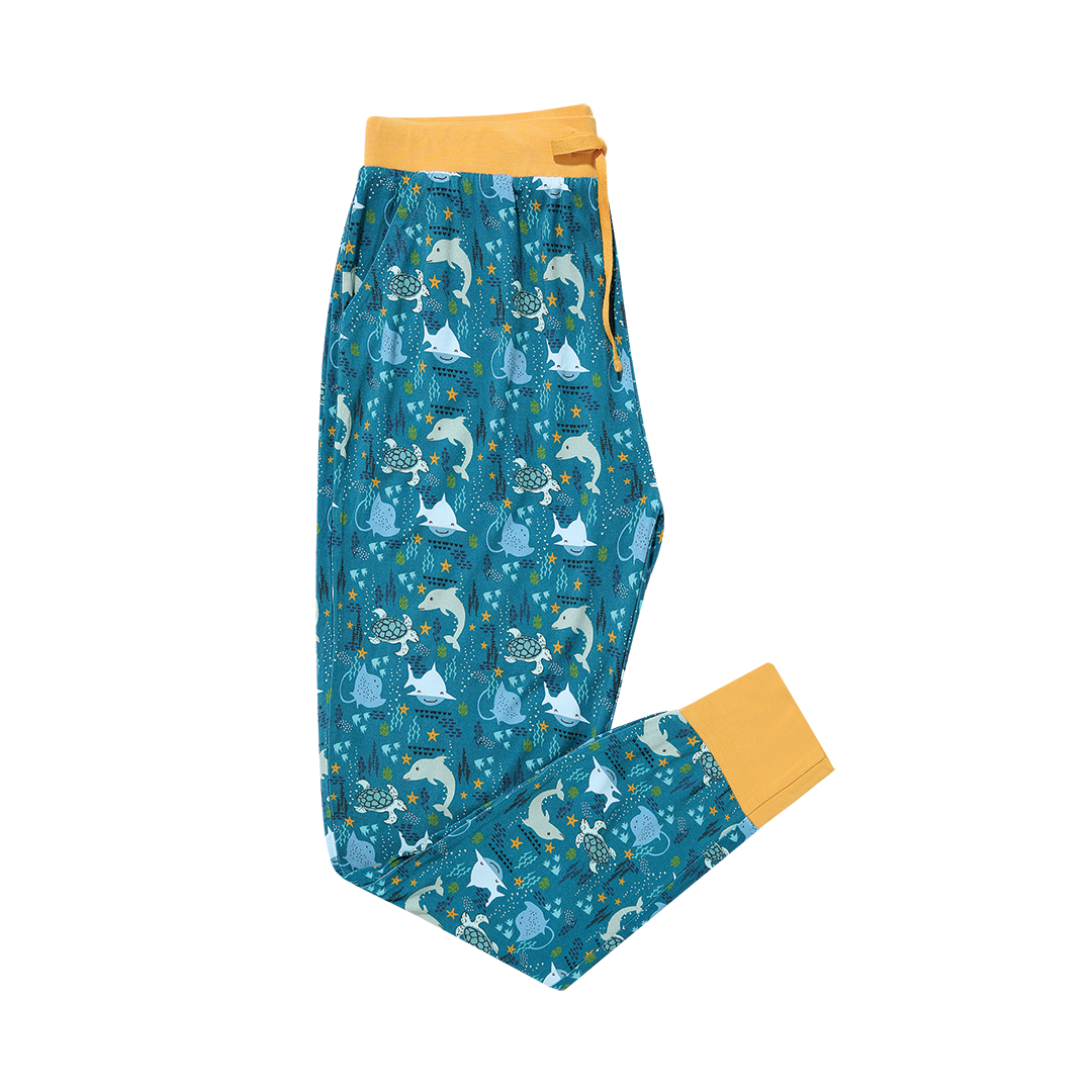 the "ocean friends" women's jogger pants. the "ocean friends" print is a combination of dolphins, stingrays, fish, starfish, coral, bubbles, and sharks, all spread out on a deep sea blue background.