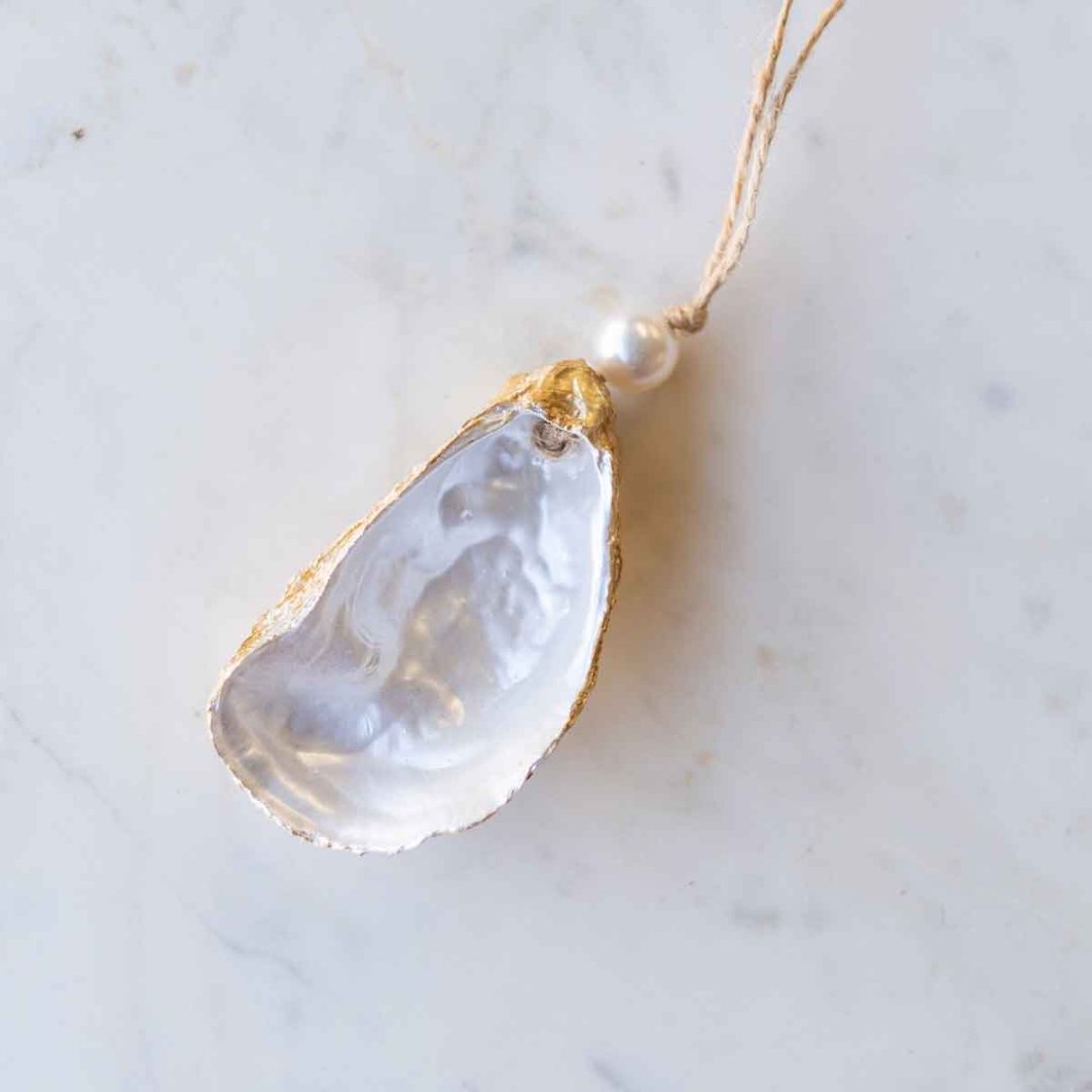painted oyster shell ornament with a pearl bead on top