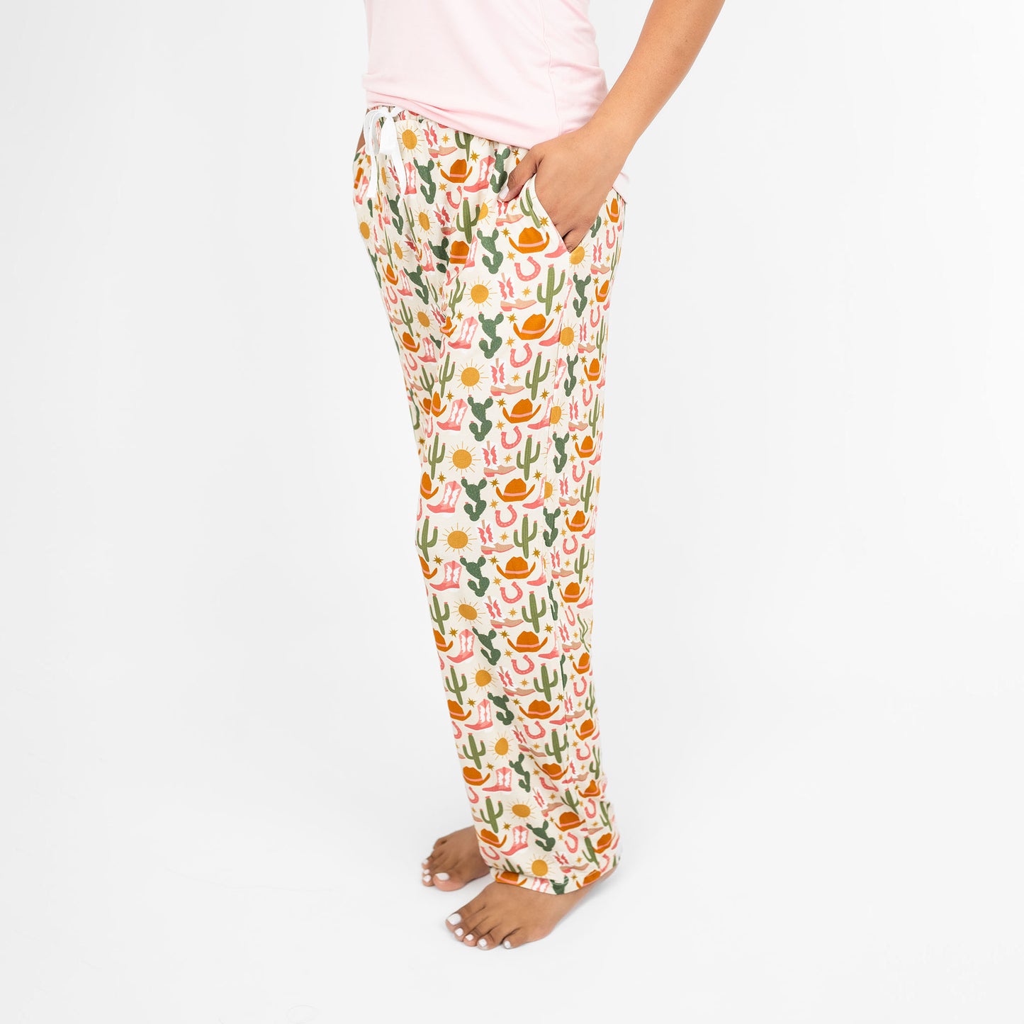 Woman wearing our Emerson and Friends Hey Y'all relaxed pajama pants adorned with a charming cactus and flower print, ideal for cozy evenings at home.