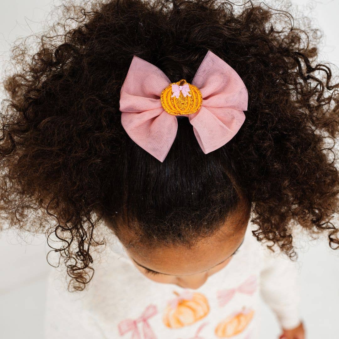 pink hair bow with an orange pumpkin in the middle