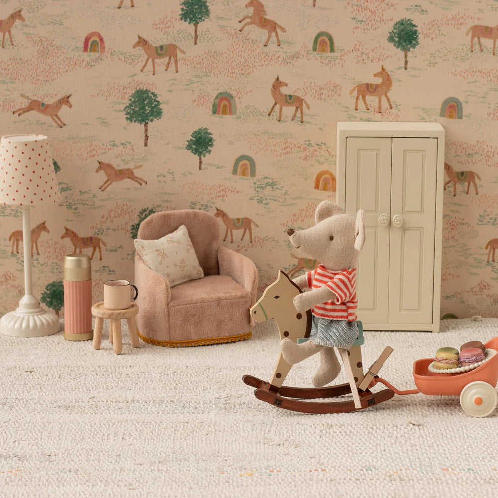Children's room with toys, chair, and lamp against a patterned wall.