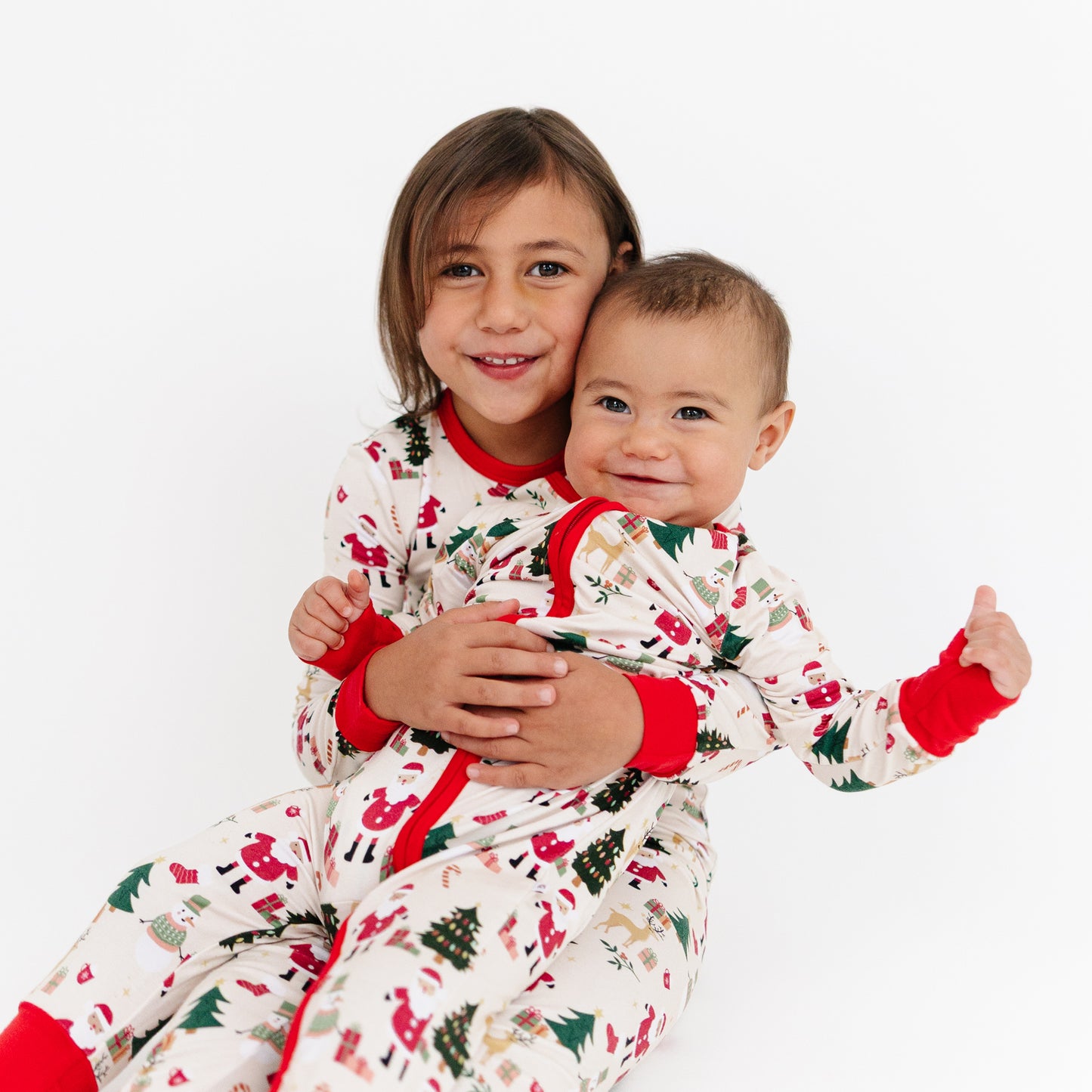 Big sister hugging her baby brother in matching Cozy Christmas bamboo pajamas – soft, festive, and photo-ready holiday sleepwear.