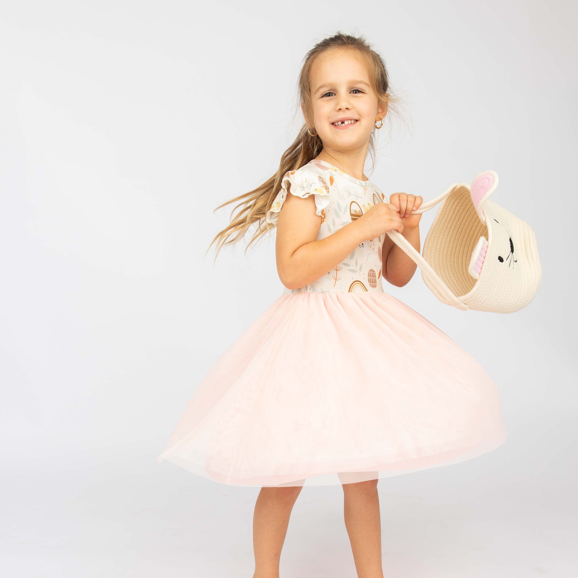 Girl holding our white bunny basket while spinning on her Bamboo easter dress.
