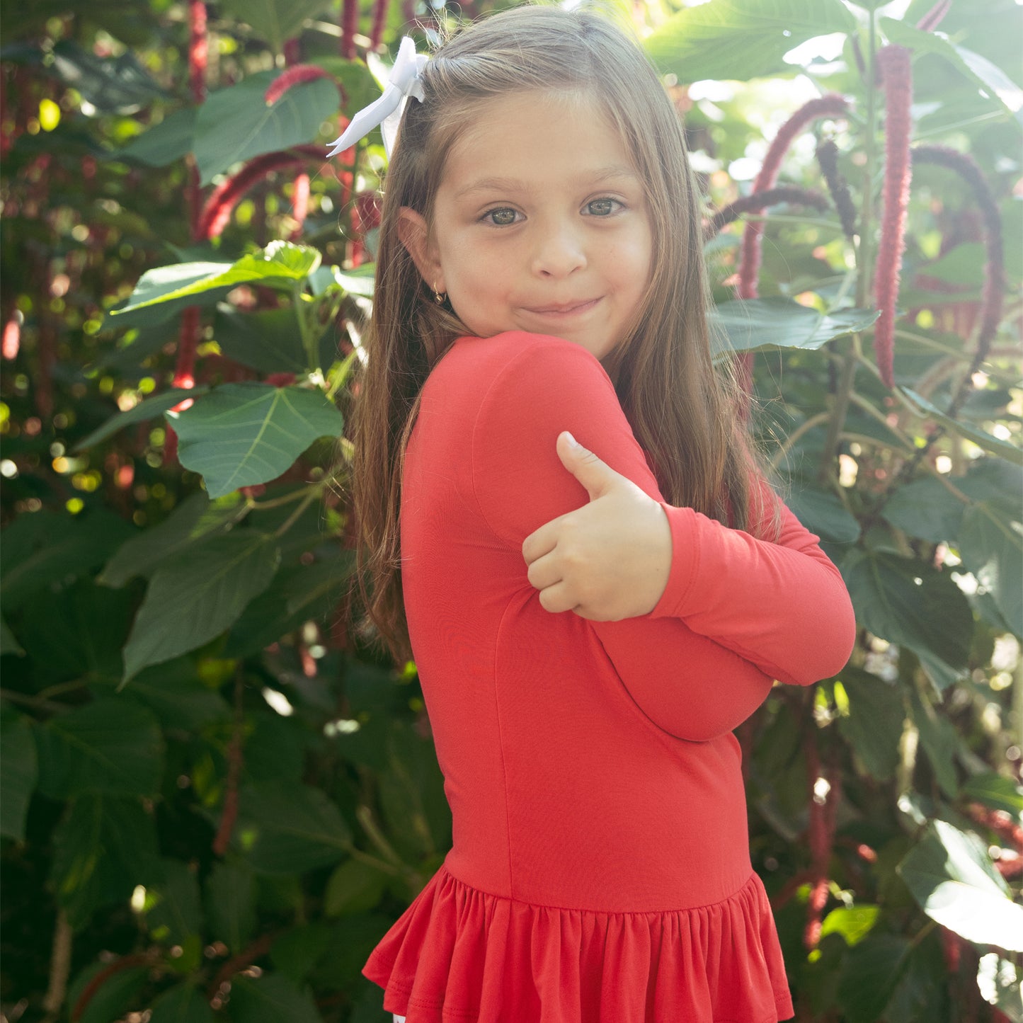 Close-up of girl smiling in Sugar Plum bamboo flare pants set with red ruffle top and holiday print pants.