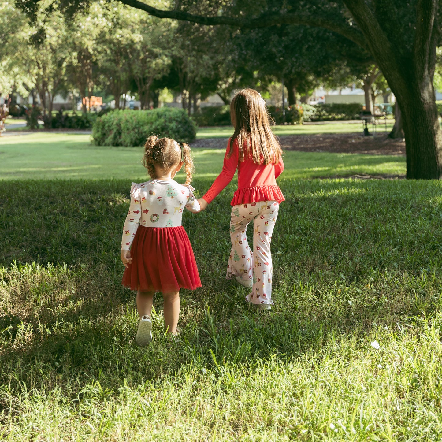 Sisters run together outdoors wearing Sugar Plum bamboo outfits, perfect for festive fun and everyday comfort.