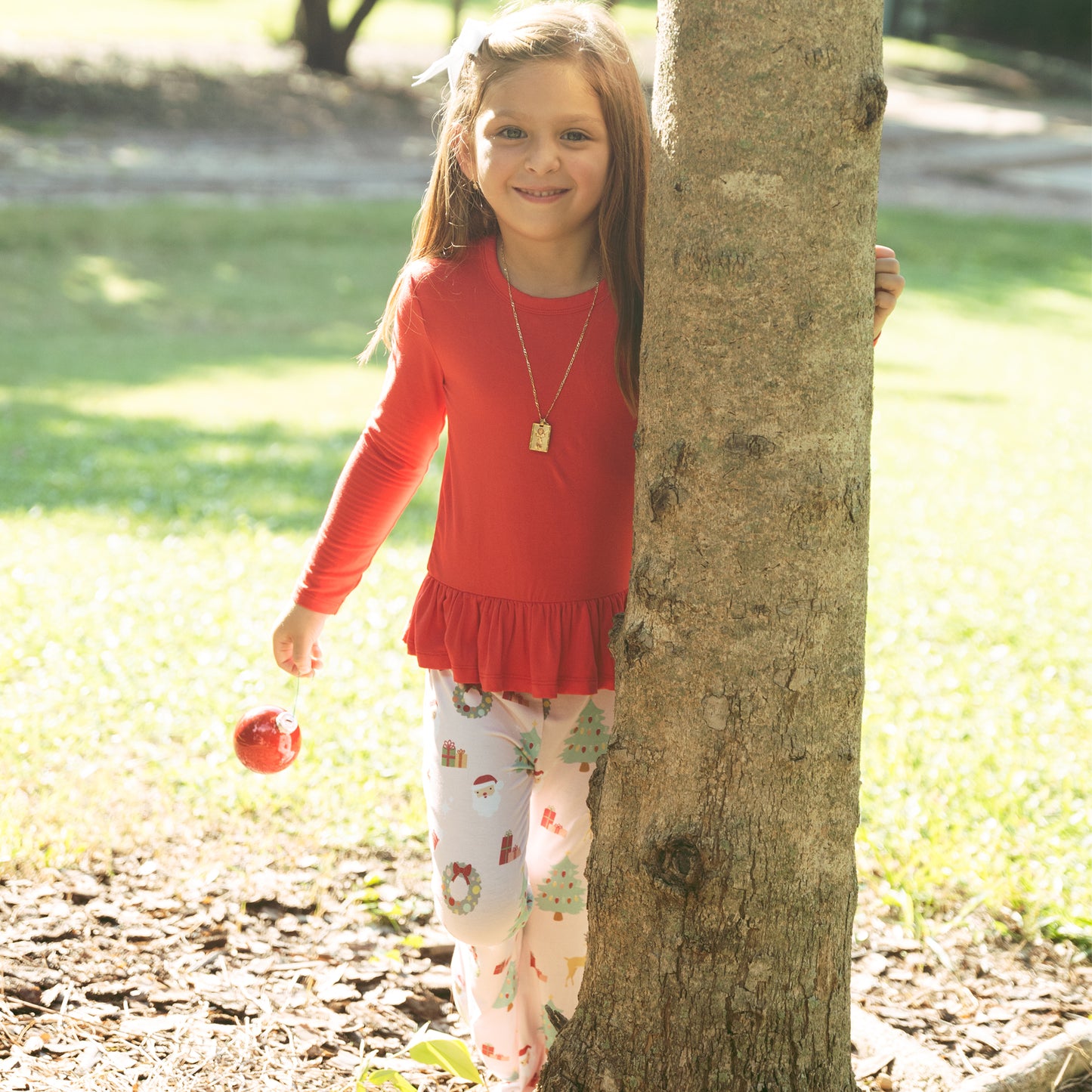 Girl wearing Sugar Plum bamboo flare pants set walks outdoors, showcasing soft fabric and festive holiday style.