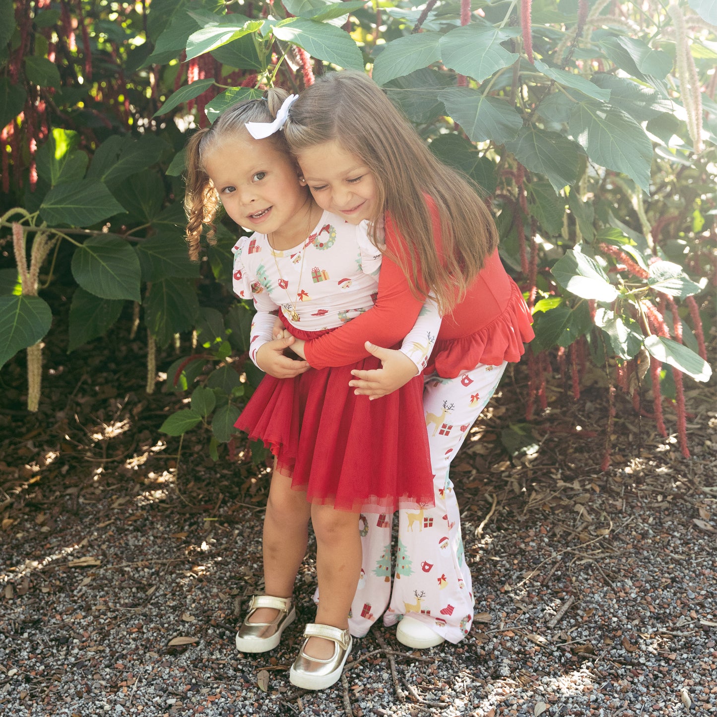 Two girls hugging in matching Sugar Plum bamboo outfits, highlighting the soft bamboo fabric and cheerful holiday design.