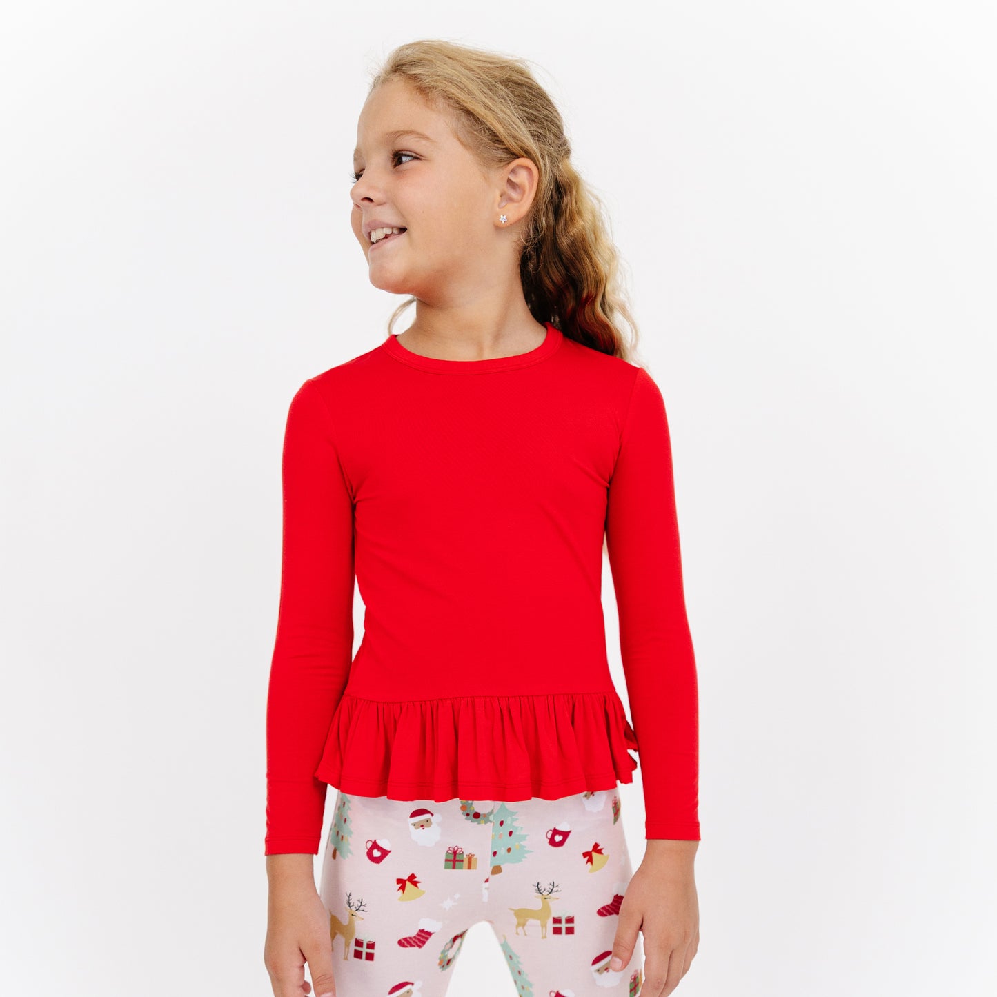 Girl poses in Sugar Plum bamboo flare pants set, featuring a red ruffle top and soft bamboo printed pants.