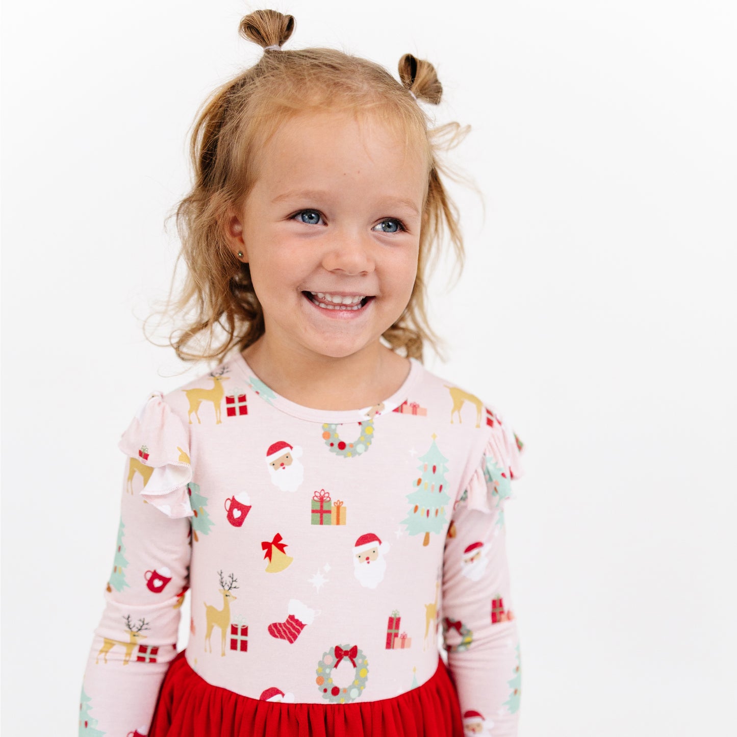Girl smiles in Sugar Plum bamboo tulle dress with festive holiday print and soft layered skirt.