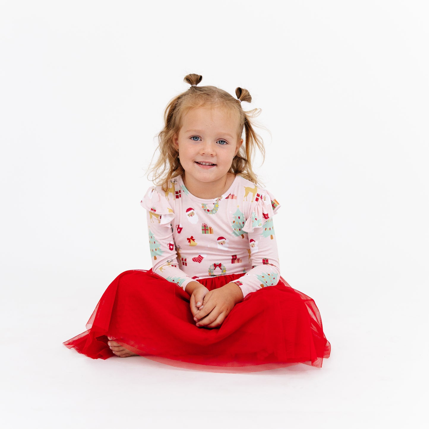 Girl sits smiling in Sugar Plum bamboo tulle dress, highlighting the cozy bamboo fabric and holiday-ready style.