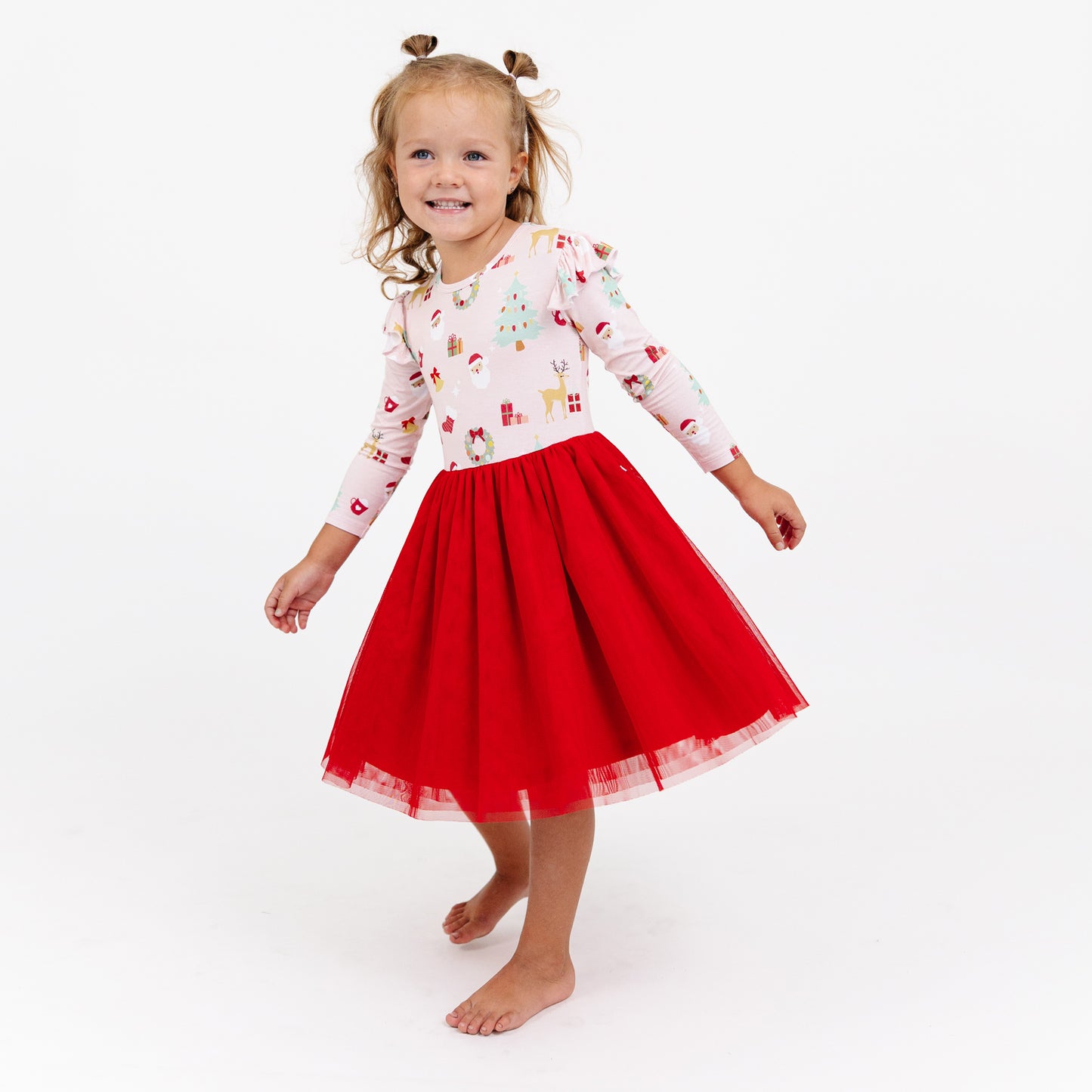 Child stands wearing Sugar Plum bamboo tulle dress, featuring a soft bamboo top and flowy red tulle skirt.