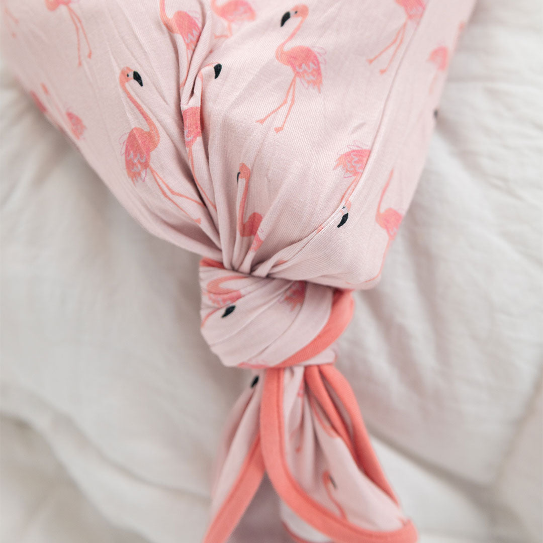 a close up of the "fancy flamingos" gown with a knot at the bottom of it. the "fancy flamingos" print is a pattern of multiple pink flamingoes scattered around the print.