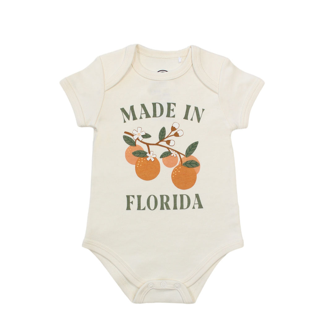 this cotton onesie has the phrase "made in Florida" in green print on the onesie. there is also a branch of oranges on it too.