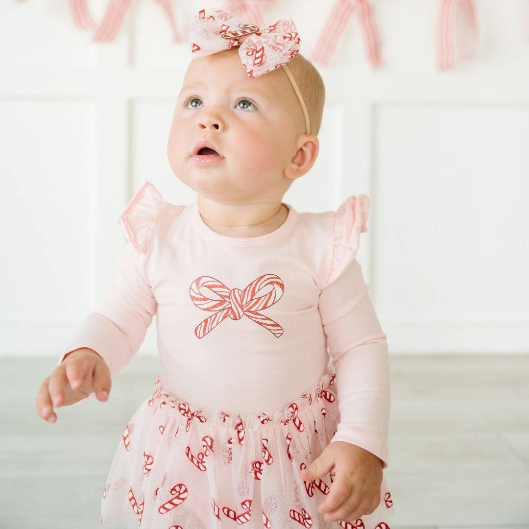 baby girl wearing a sweet wink christmas outfit thats pink with white and red candy cane accents