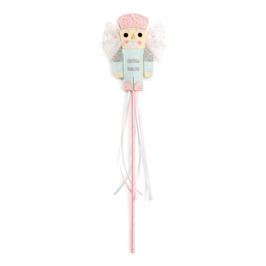 Nutcracker-themed Christmas wand featuring a pastel pink and blue nutcracker figure with glitter accents, white tulle wings, and long pastel ribbon streamers hanging from the handle.