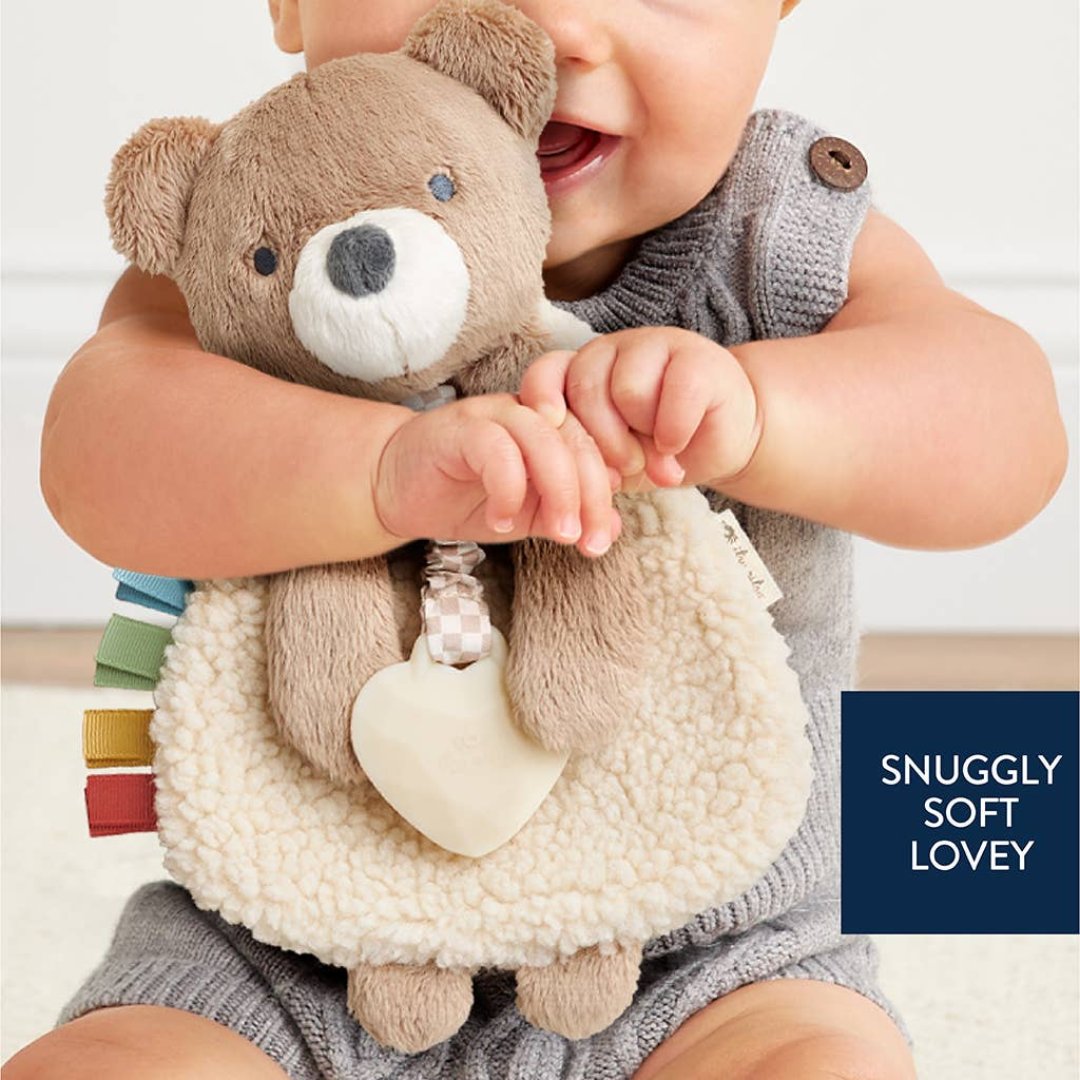 baby hugging a stuffed bear teether toy