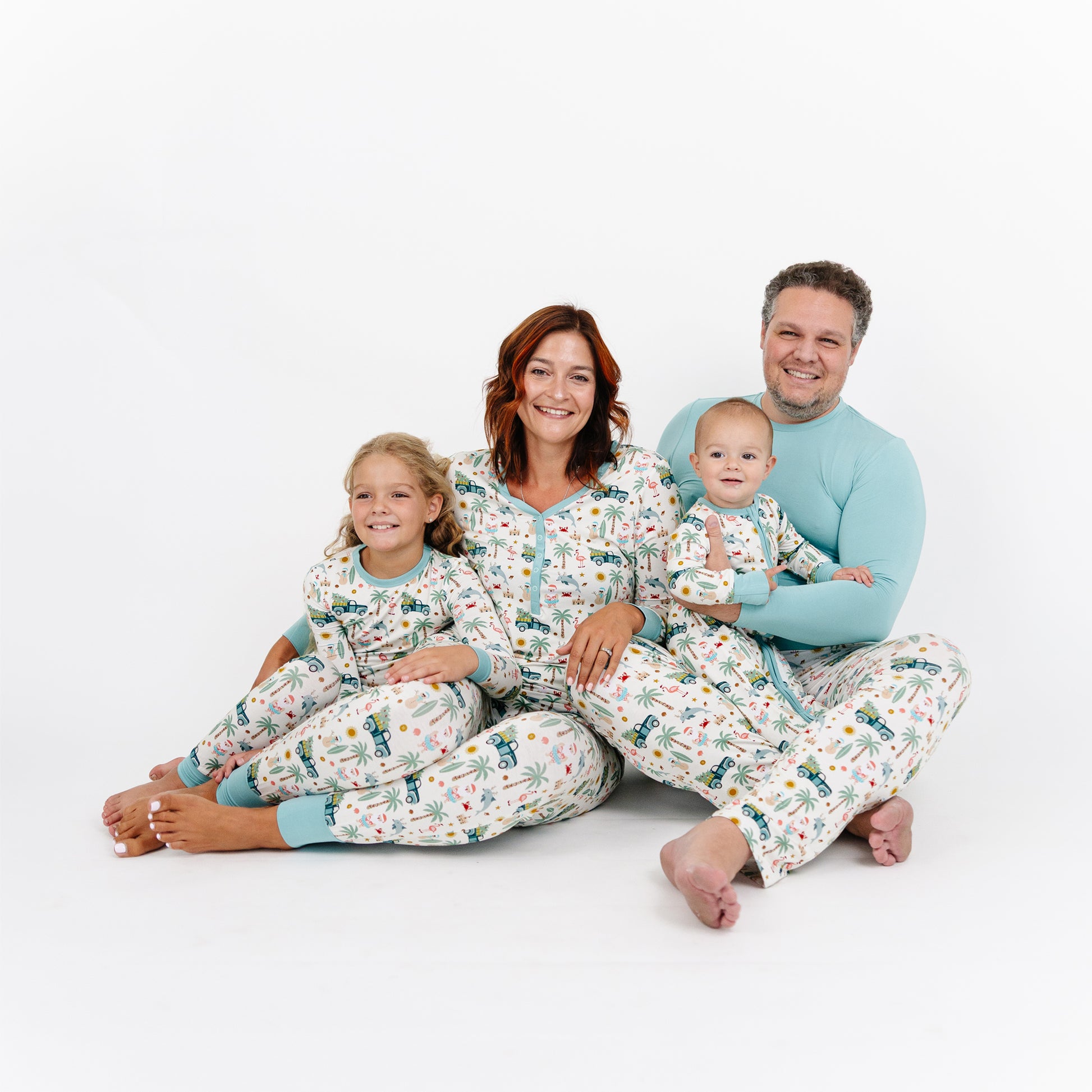 Family of four wearing matching pajamas on a white background