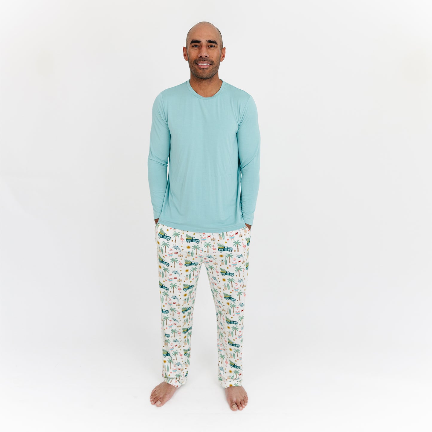 Man wearing a light blue pajama top and patterned pants on a white background