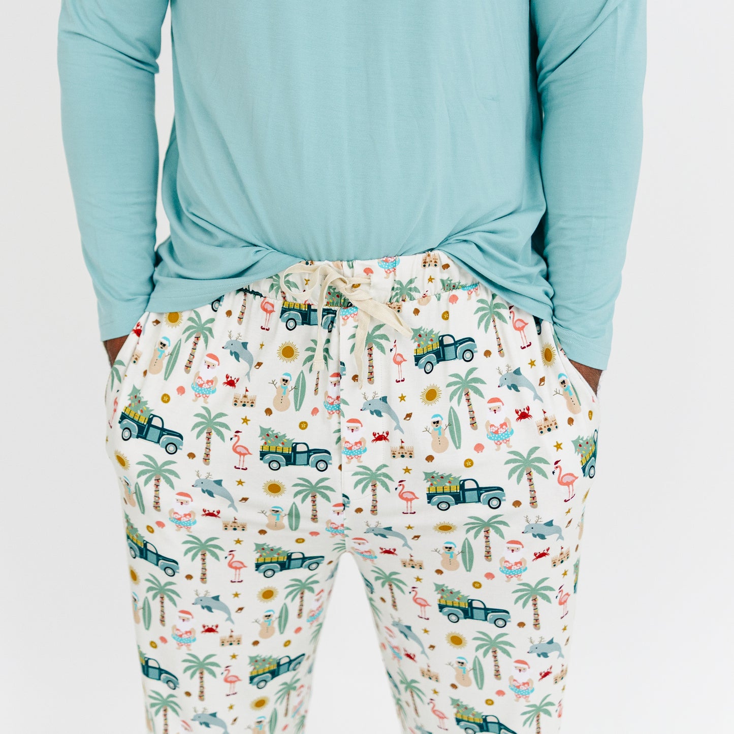 Person wearing light blue long-sleeve top and patterned pajama pants with tropical design.