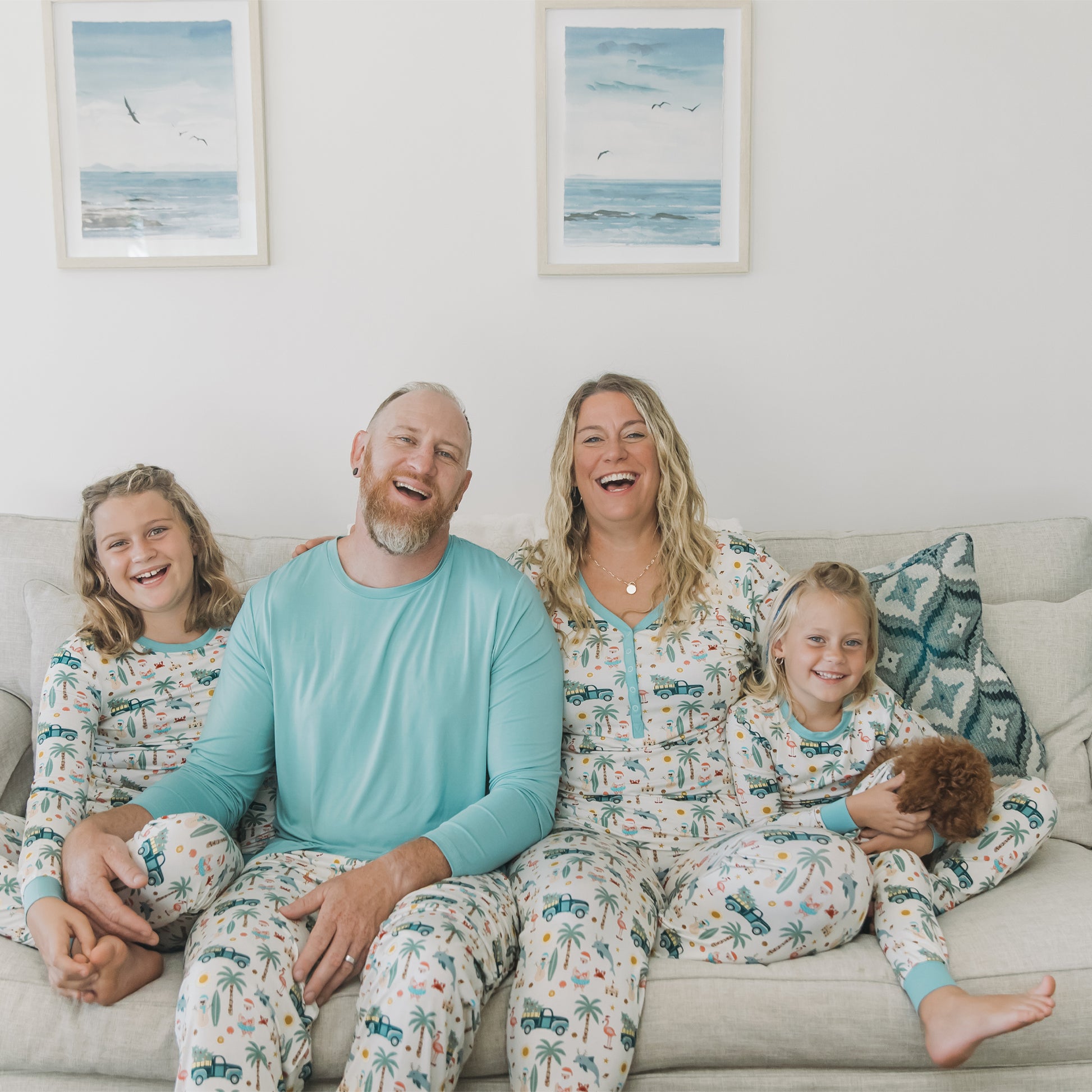 Family of four sitting on a couch wearing matching pajamas in a cozy living room.