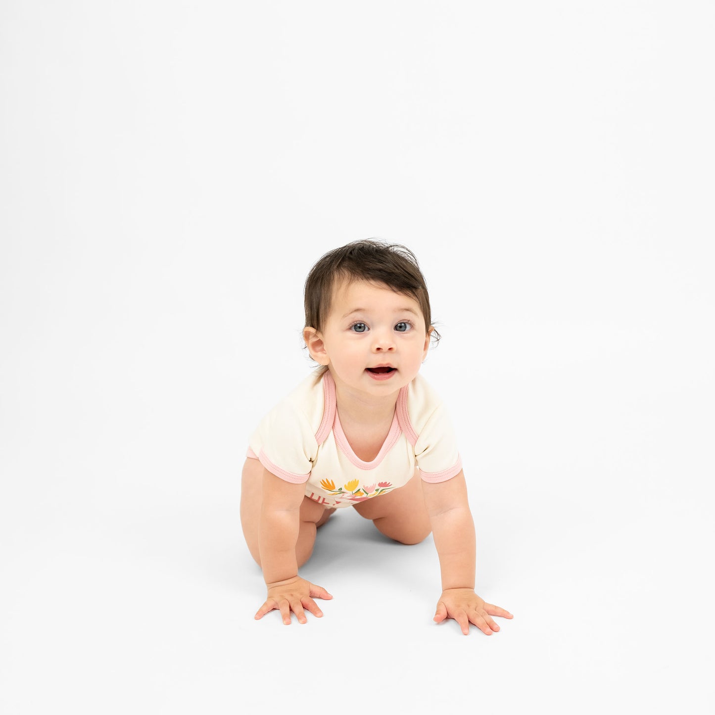 Cute baby girl crawling while wearing our Hey Y'all onesie paired with a pink cowgirl boots print and floral accents, capturing the essence of rodeo and western style for a perfect outfit.