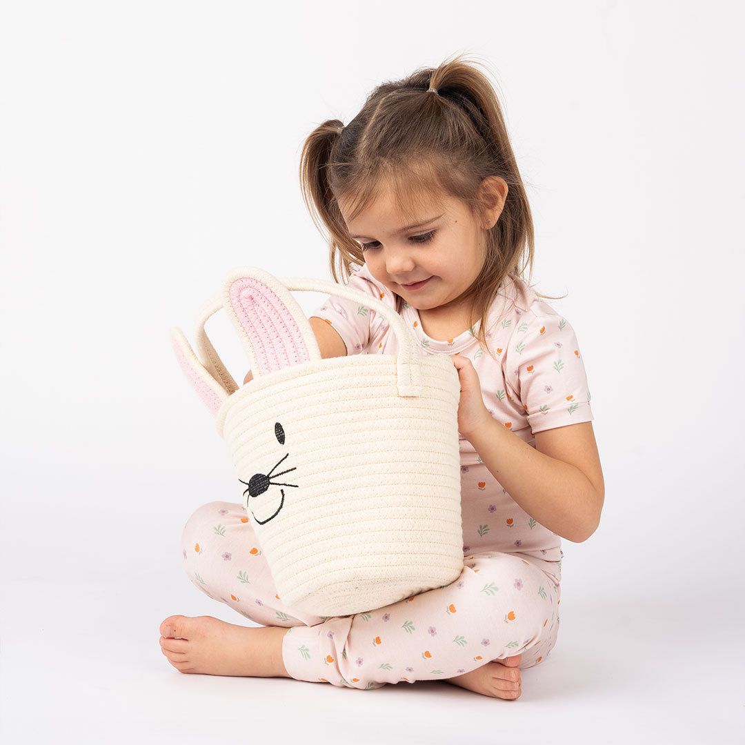 Girl looking inside and reaching for something from the white bunny basket.