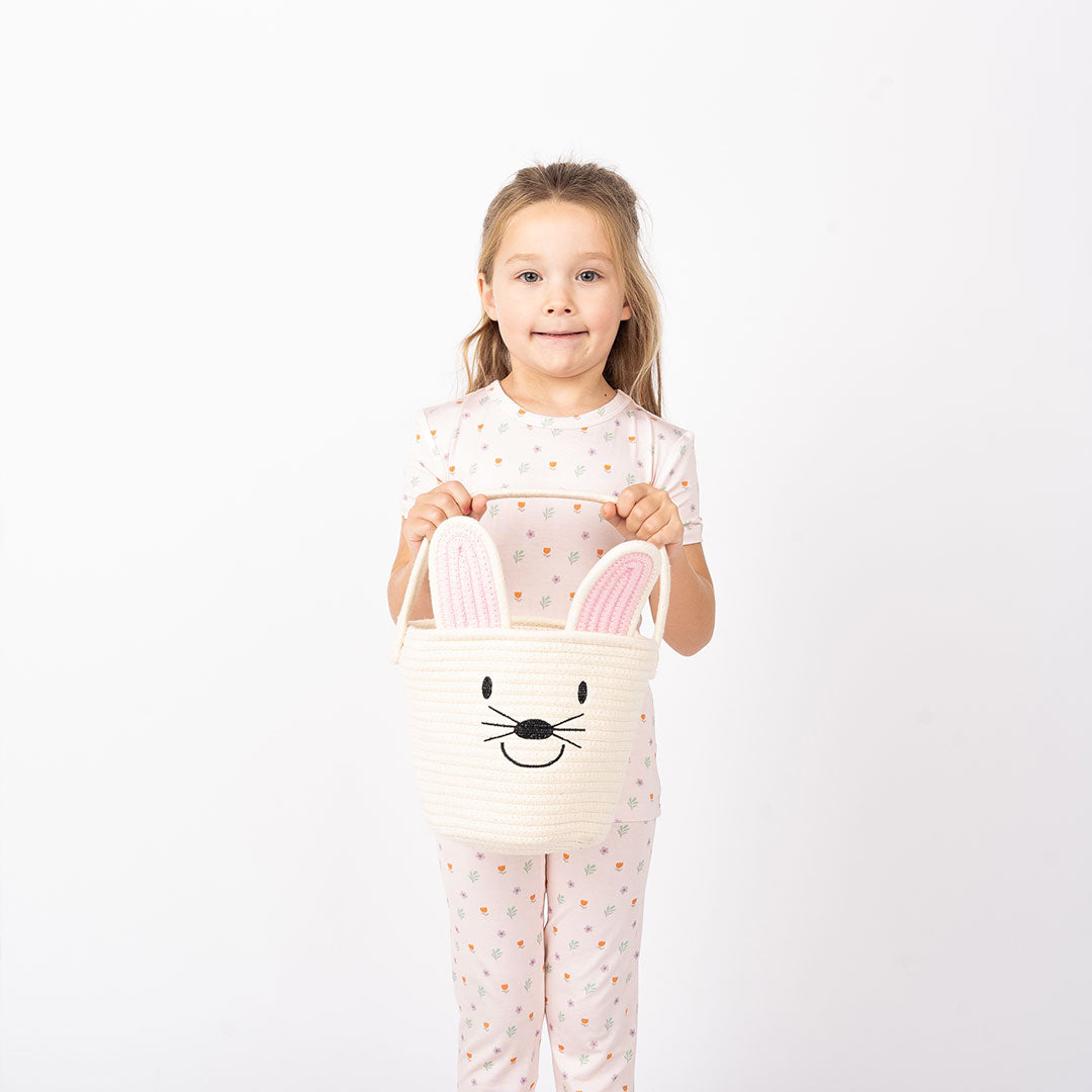 Girl holding our white bunny basket. while wearing the bamboo breathable pajama.
