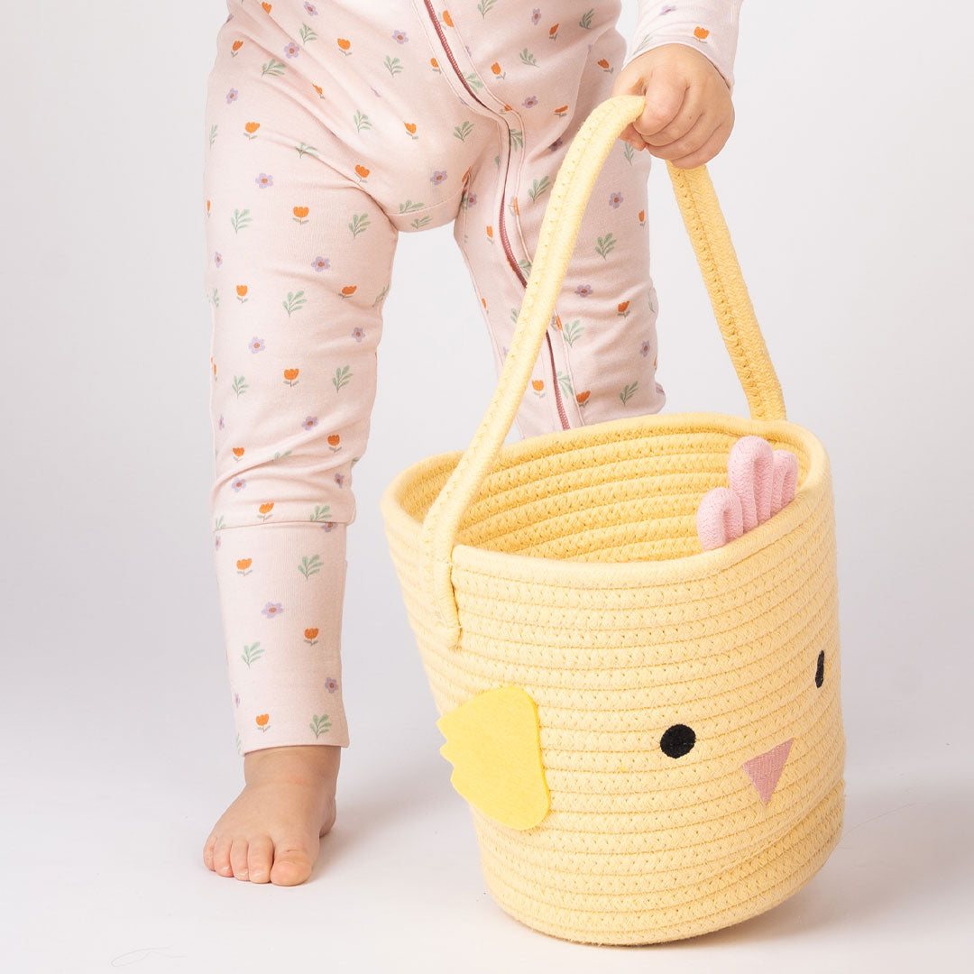 Little girl holding our yellow chick basket, with focus on the basket and her legs, set against a white background.