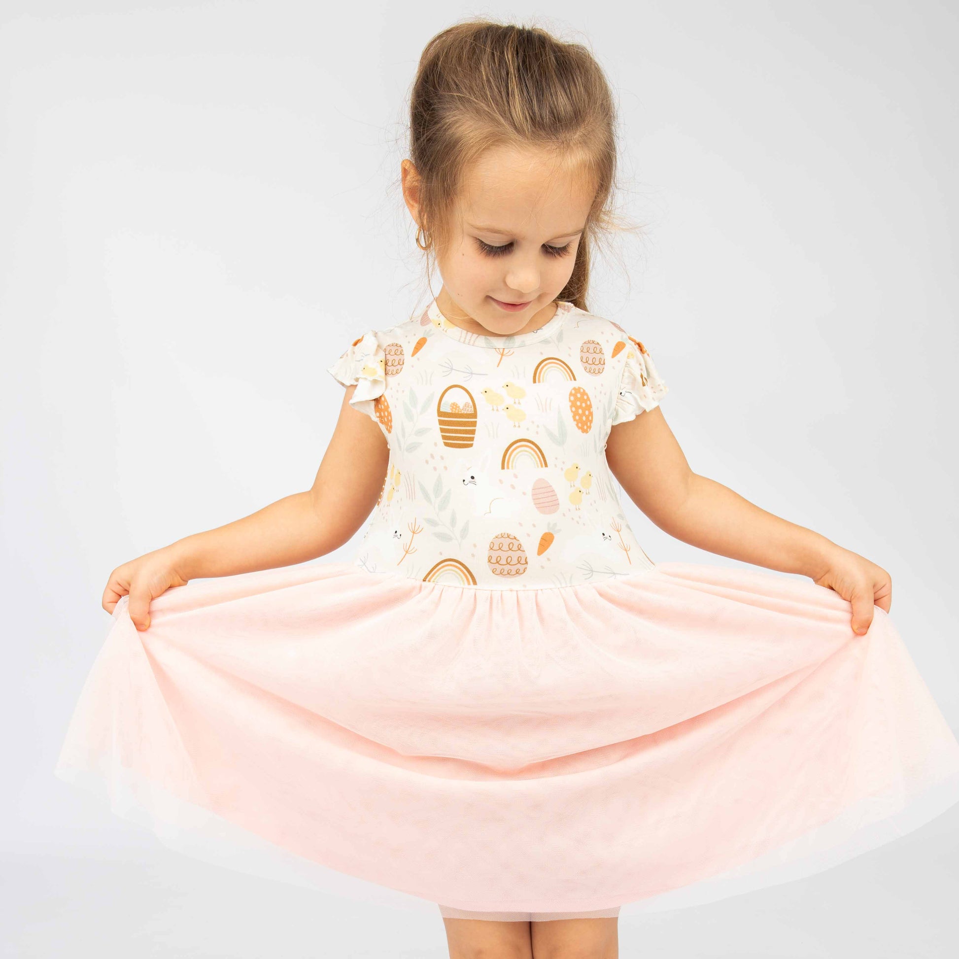 Girl playing with her tulle dress with our Hop to It print that features eggs, chicks, bunnies and more!