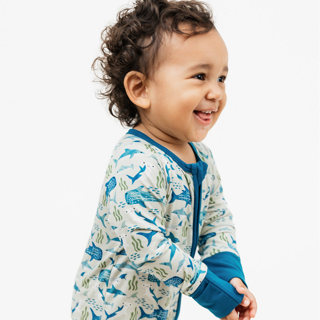 Baby smiling while standing in our Shark Friends Bamboo Convertible Pajama.