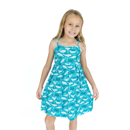 Young girl wearing a blue dress with white whale pattern on a white background