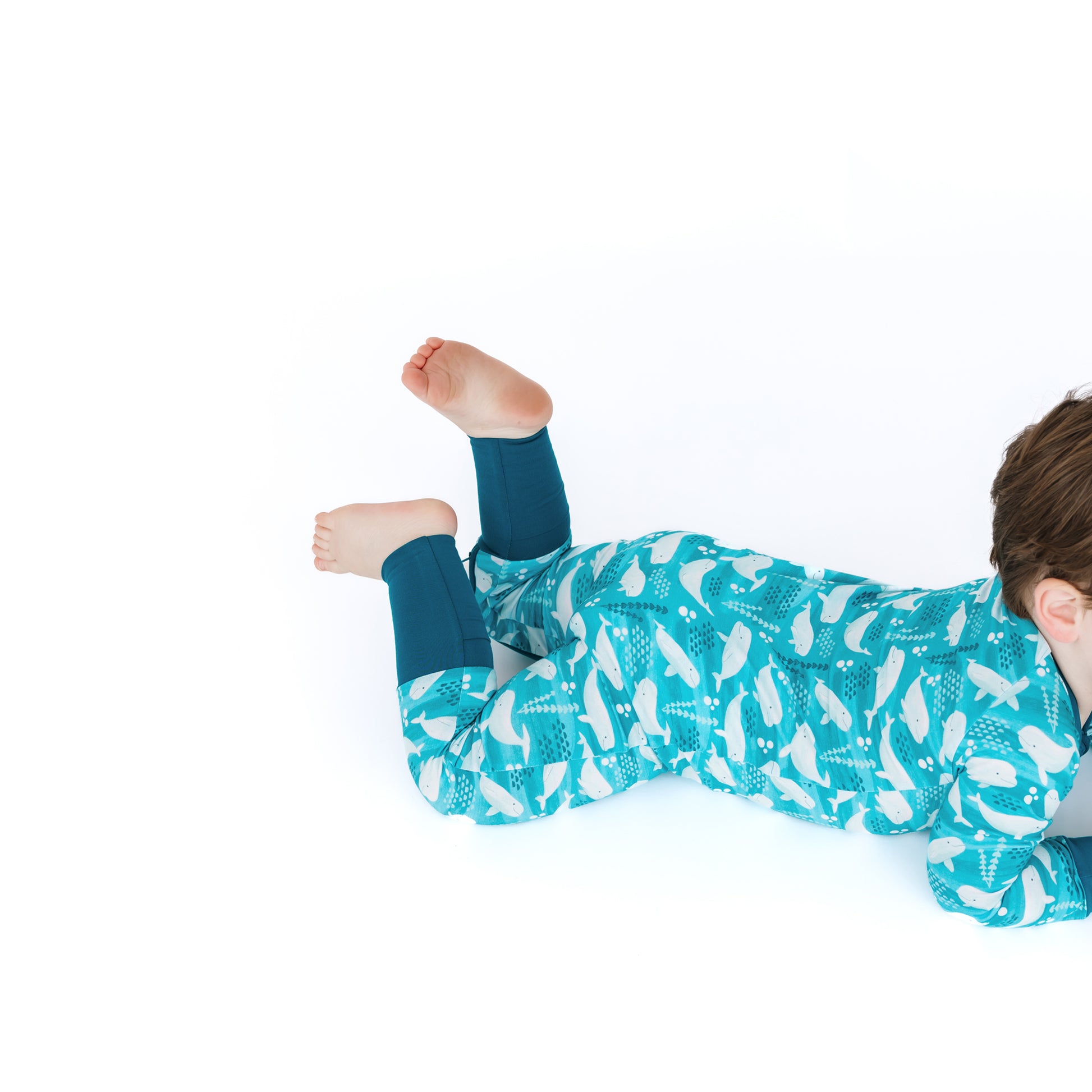 Child wearing a teal onesie with white patterns on a white background