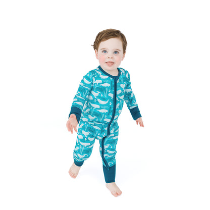 Child wearing a blue onesie with whale pattern on a white background