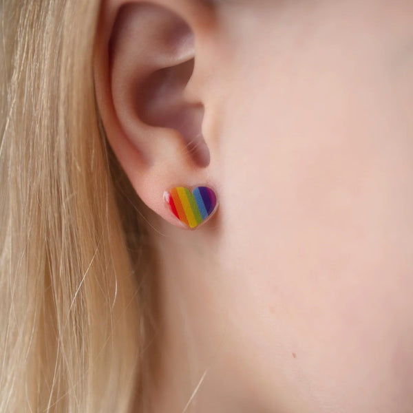 Close up of a little girl's ear wearing rainbow striped, heart shaped sticker earrings from Great Pretenders