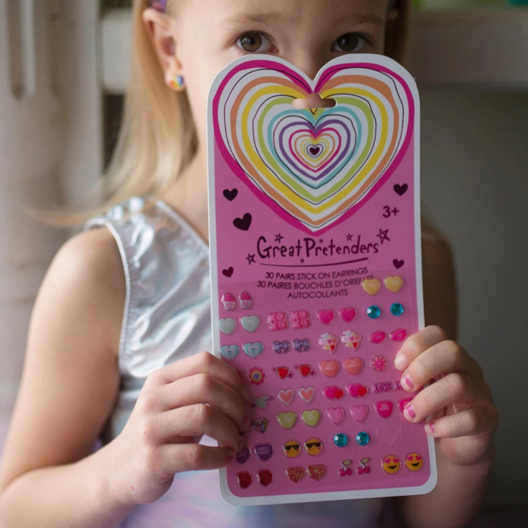 Little girl holding a sheet of heart shaped sticker earrings from Great Pretenders