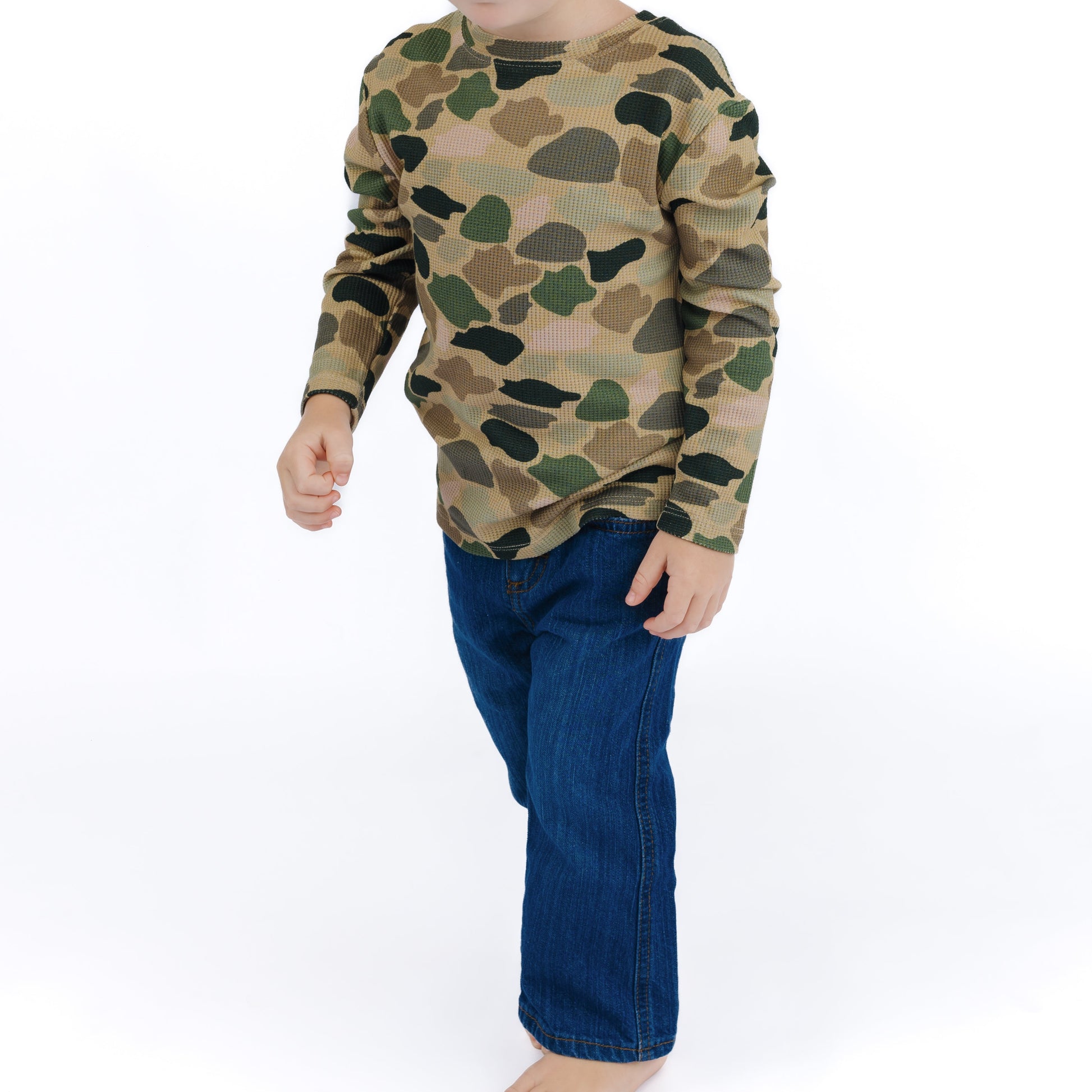 little boy wearing camo print long sleeve and jeans.