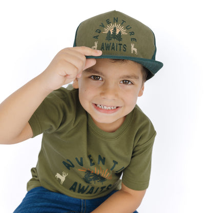 little boy wearing forest green hat with adventure awaits stitching.