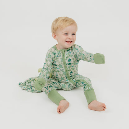 Baby boy sitting on a white background wearing our Save the Sea Turtles bamboo convertible baby pajamas by Emerson and Friends. This ultra-soft, eco-friendly footie features a charming sea turtle and ocean-inspired print. Made from breathable bamboo fabric, it’s perfect for sensitive skin and designed for ultimate comfort with fold-over feet and mittens.