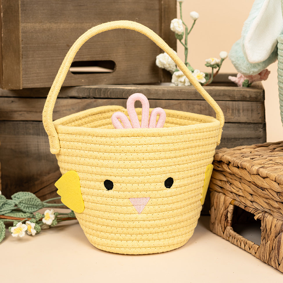 Yellow chick basket on the floor, surrounded by wooden baskets, a woven flower, and bunny ears in the background.