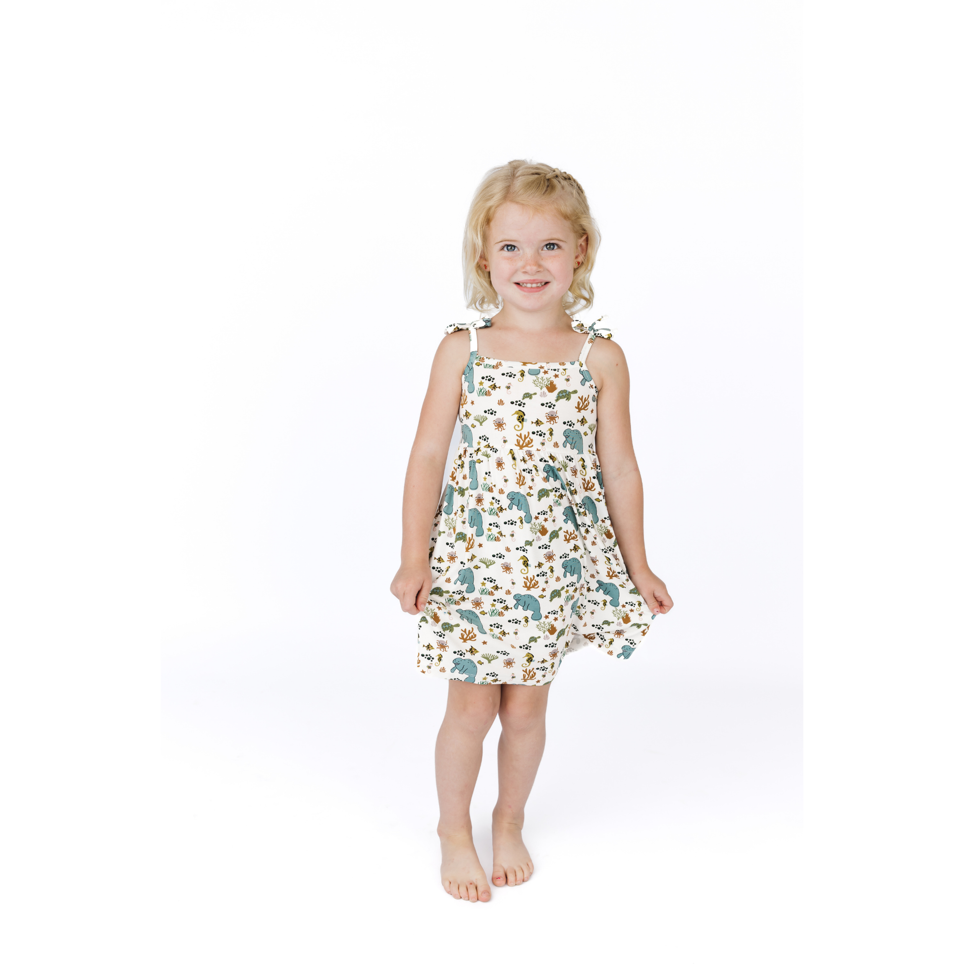 Young girl wearing a manatee patterned dress on a white background