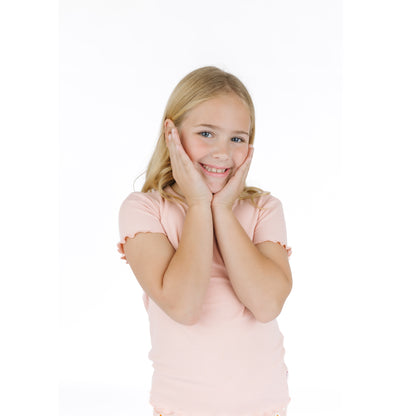 Young girl in a pink shirt posing with hands on face against a white background