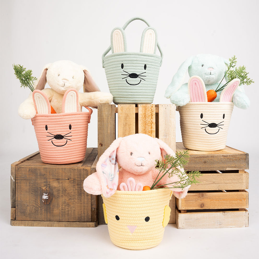 A variety of baskets in pink, white, yellow, and blue displayed on top of wooden boxes with a white background.