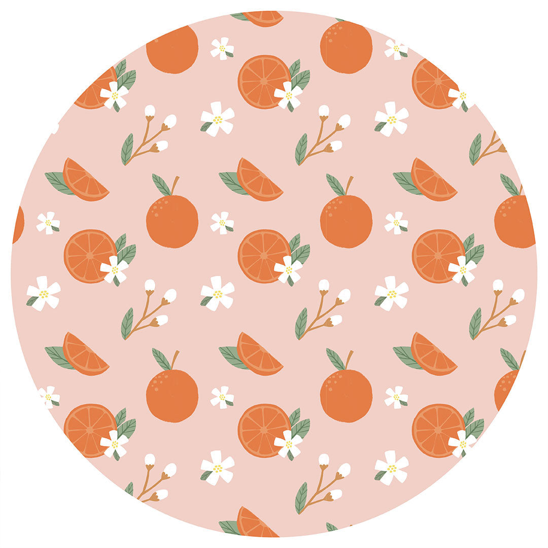 the "freshly squeezed" print has an assortment of full and half cut oranges scattered around. there is also flower heads and flower stems that intermingle within the print. this is all space out around a pink background space. 