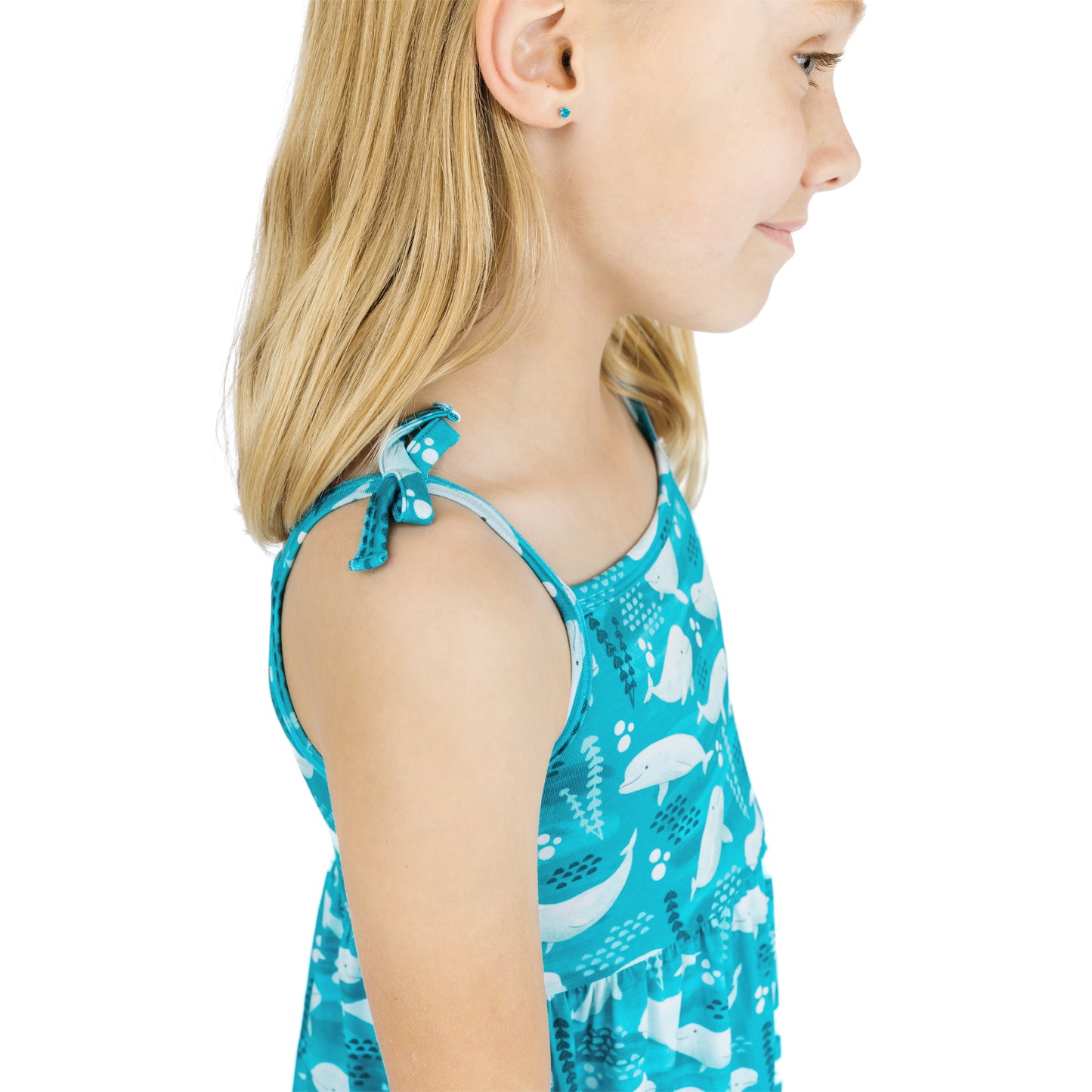 Child wearing a blue tank top with whale pattern on a white background
