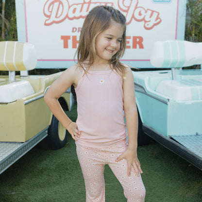 Young girl in a pink dress with greenery in the background
