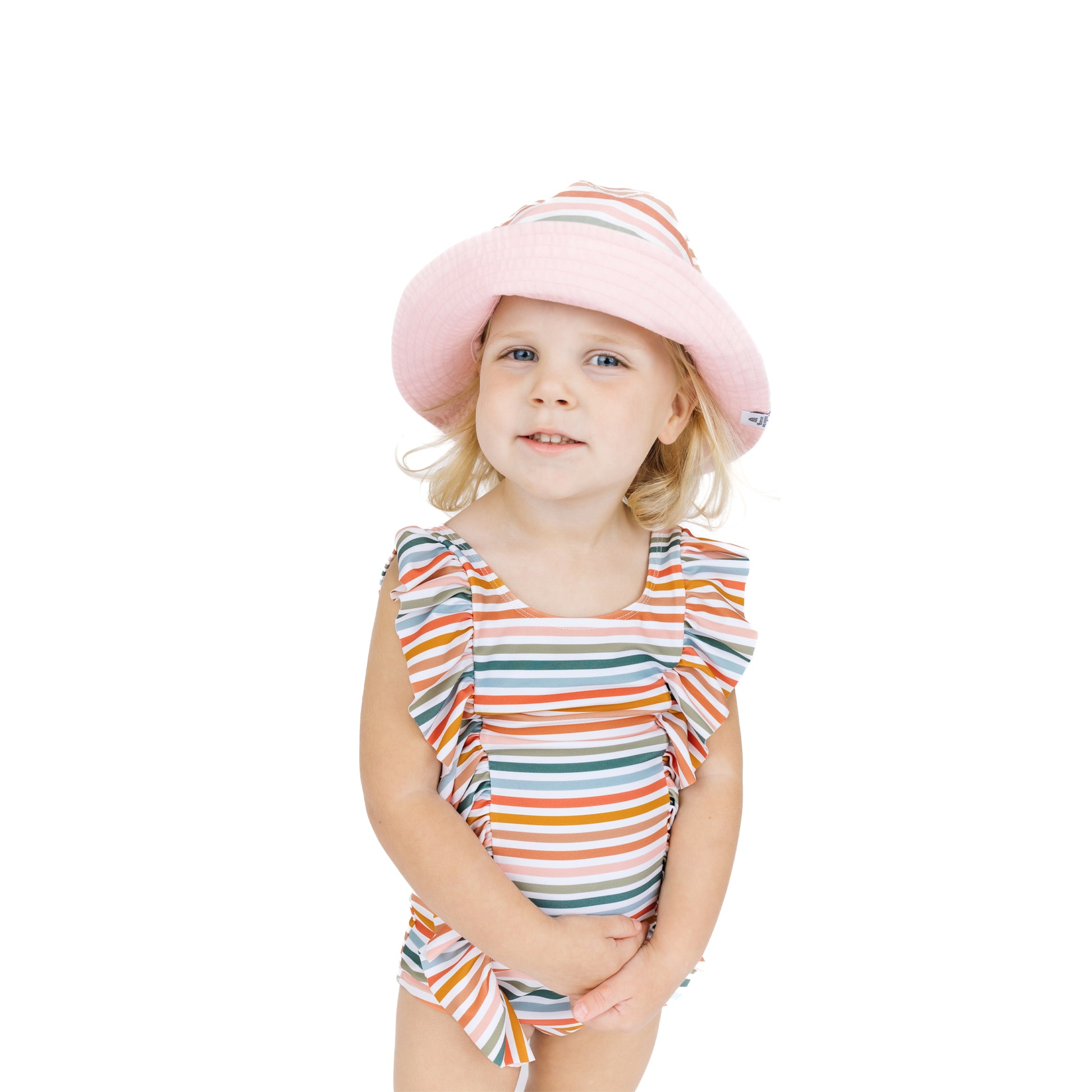 Young girl wearing a colorful striped swimsuit and pink hat on a white background