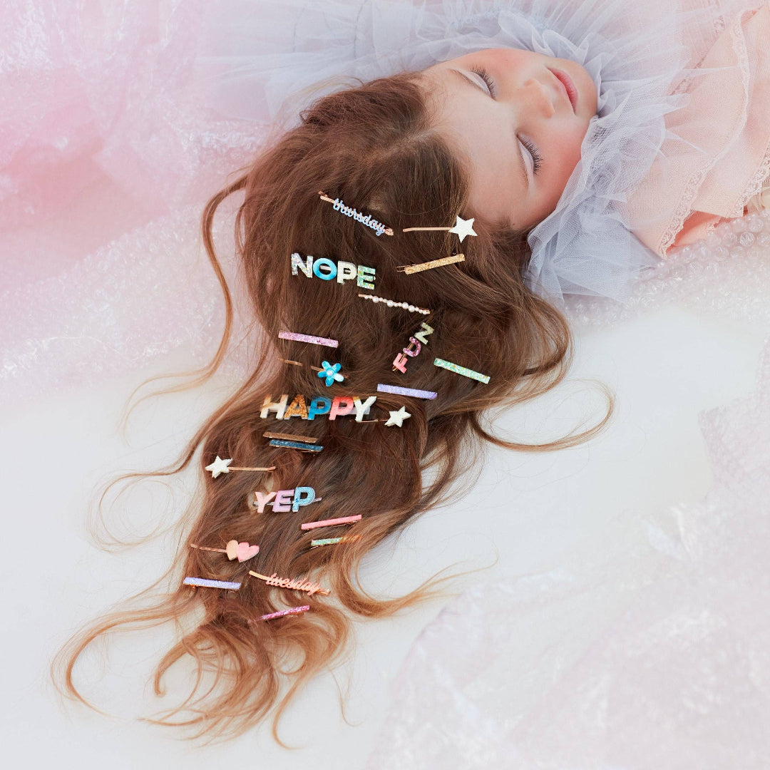 Child with colorful hair clips on a soft pink background