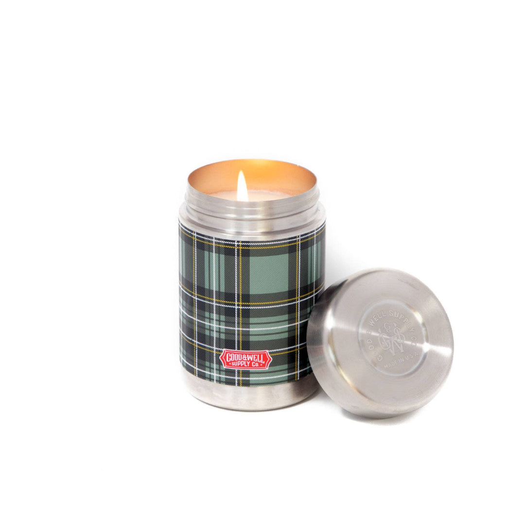 Candle in a plaid-patterned tin with a metal lid on a white background