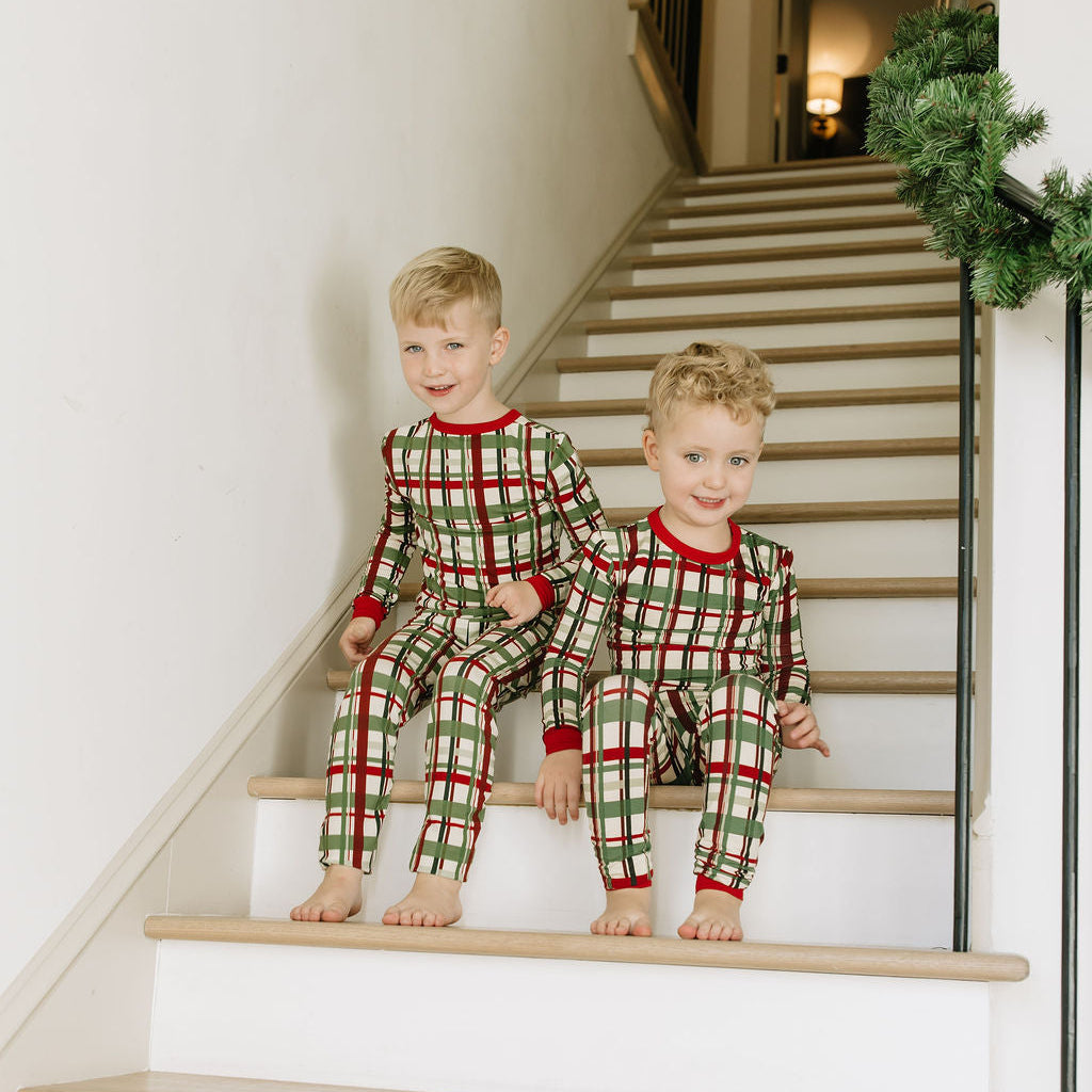 Two boys matching in bamboo holiday plaid pjs in the house stairs 